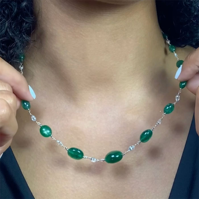 person wearing a graduated emerald and diamond briolette necklace