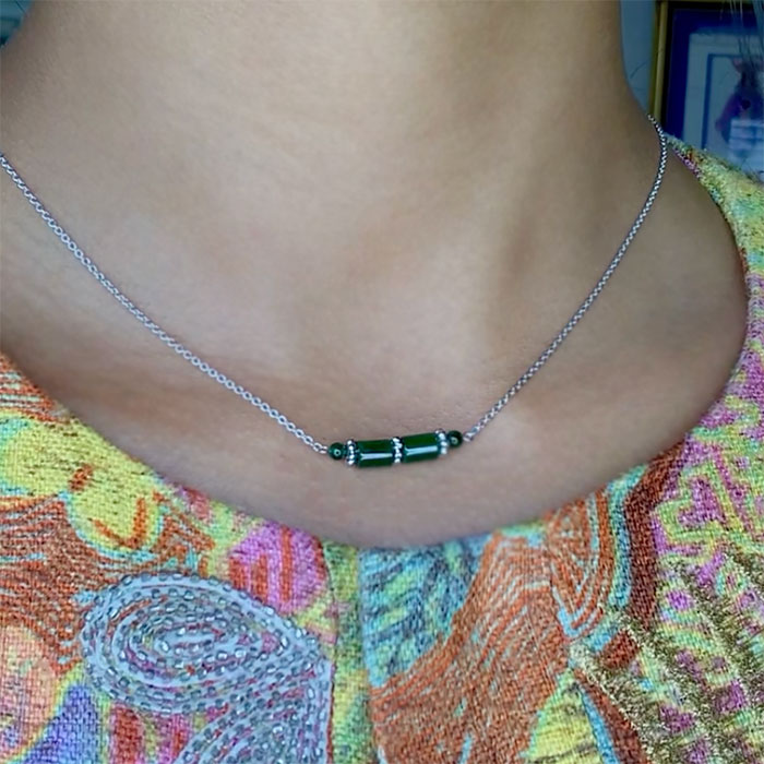 person wearing a green jade bar necklace