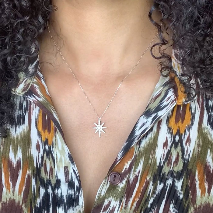 Person wearing a diamond star pendant in white gold