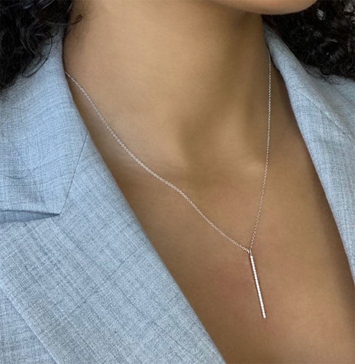 person wearing a white gold diamond vertical bar necklace